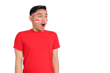 Shocked young Asian man celebrating Indonesian independence day looking at copy space with open mouth isolated on transparent background