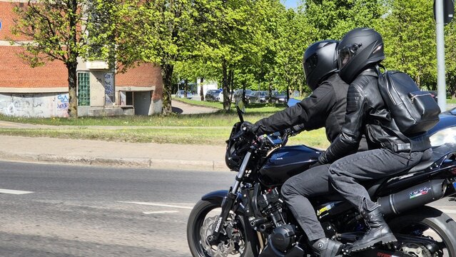 Vilnius Lithuania - 05.03.2025 OPENING OF THE VILNIUS REGION'S MOTORCYCLING SEASON 2025 Two bikers in black gear riding a Honda motorcycle on city street