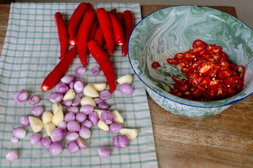 closeup shot of red hot chili peppers, garlic and red onions on cutting wood in the kitchen