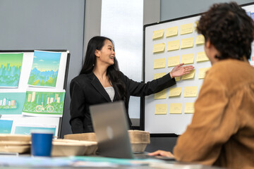 Asian professional businesswoman presenting project with sticky notes on whiteboard in creative...