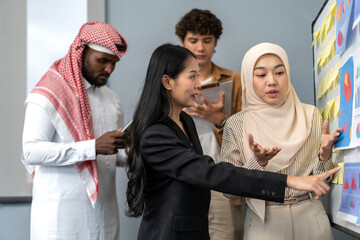 Diverse team analyzing charts and sticky notes on whiteboard during business meeting, arab, asian and muslim coworkers discussing data insights, teamwork, corporate strategy, startup planning session