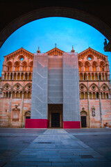 The Cattedrale di Ferrara, a landmark cathedral in Piazza della Cattedrale, seen through an arching corridor during maintenance in Emilia-Romagna, Italy—where tradition meets renewal