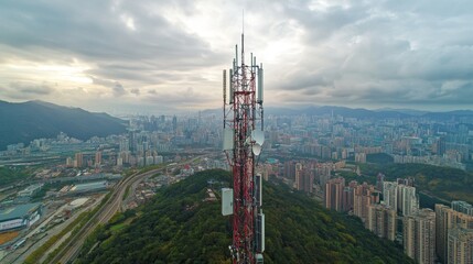 Obraz premium Urban Landscape Showcasing a Telecommunications Tower Overlooking a City Skyline During Cloudy Weather With Distant Mountains and Infrastructure Below