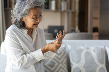 Elderly asian woman holding wrist pain, arthritis, health issue, senior female suffering from joint...