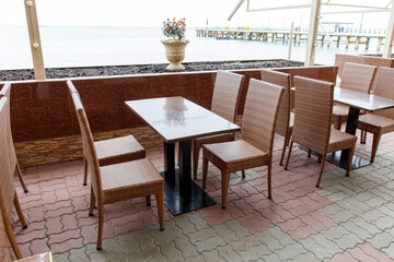 A patio with a table and chairs outside. The table is surrounded by chairs and there is a potted plant in the background. The chairs are arranged around the table, and there are several of them