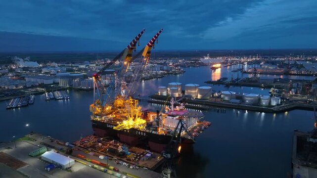 Rotterdam, Netherlands. Drone flight over industrial area with cargo ports, containers and a semi-submersible ship, heavy lifting crane. Machines designed for work at sea