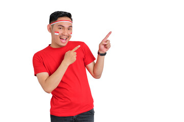 Cheerful young Asian man celebrating Indonesian independence day pointing aside at copy space...