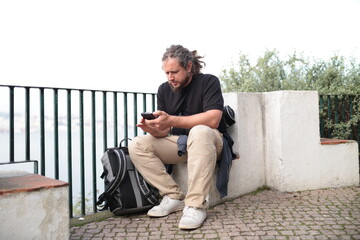 Tourist using smartphone while resting on scenic overlook