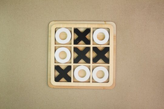 A wooden game set of noughts and crosses on a black background, tic-tac-toe. Tic tac toe educational game. Strategy concept