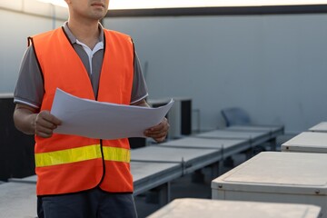 Asian maintenance engineer works on the roof of factory. contractor inspect compressor system and...