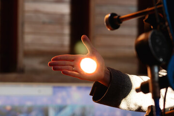 Man holds his hand up, capturing focused telescope light. The projection of the solar disk on the palm
