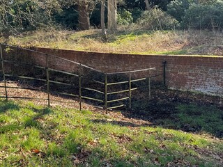 Metal fence leading down short slope to wall