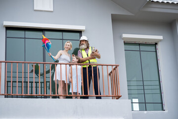 Caucasian mother and daughter play pinwheel with engineer builder holding tablet computer at Housing Development Under Construction