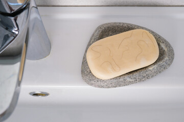 White soap in a soap dish with hair on the sink