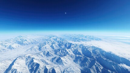Breathtaking aerial view of snow-covered mountain range under clear blue sky with a visible moon and vast icy landscape expansive terrain in high altitude