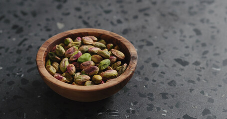 peeled pistachios in olive bowl on terrazzo surface