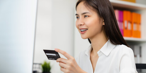 female hand holding credit card and type on laptop keyboard with online payment for shopping.