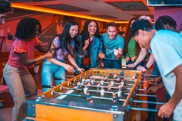 Excited friends playing table football in an amusement arcade