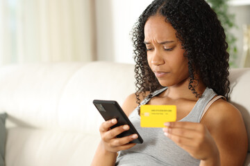 Worried black woman paying online with phone