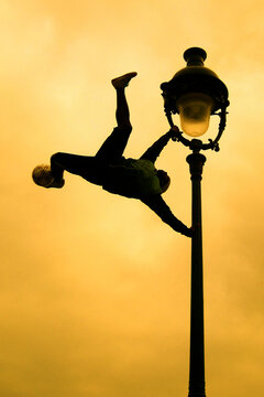 Healthy fit man climbing on lamp post Paris football during sunset