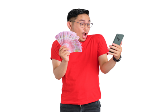 Shocked young Asian man using mobile phone and holding money banknotes isolated on transparent background