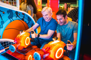 Two friends playing and having fun with arcade games in entertainment center