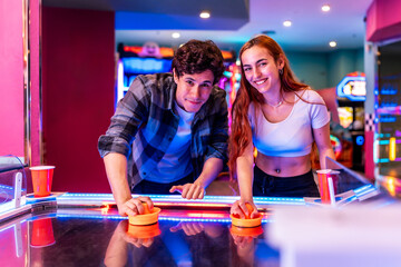 Young couple playing air hockey in entertainment center