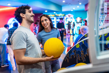 Happy couple playing arcade basketball game together on a weekend out