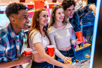 Young multiethnic friends playing arcade games and enjoying weekend together