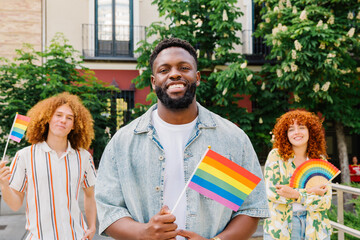 Multiracial friends waving rainbow flags, cheering during pride event, expressing solidarity and...