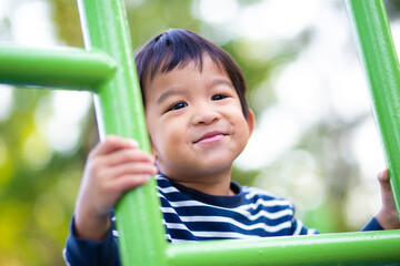 Adorable little asian 2 - 3 year boy climbing practice  in playground outdoor