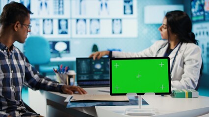 Female general practitioner and patient looking at green screen on tablet, recommending pills and...