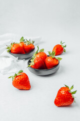 Fresh, ripe strawberries in black bowls on a light background