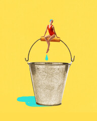 Woman in red swimsuit sits on metal bucket handle with drop falling below against yellow background. Contemporary art collage. Concept of summer, vacation, surrealism, creative design © master1305