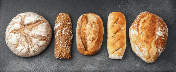Different types of bread displayed on a dark surface in a bakery setting