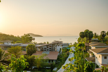 Serene Coastal Village Under Setting Sun with Islands in the Background