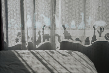 Nursery room with dinosaur shadows on curtain.