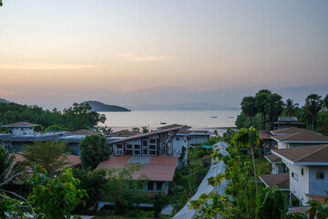 Serene Coastal Village Under Setting Sun with Islands in the Background