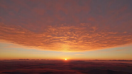 Sunrise over a vast, hazy landscape with a fiery, textured sky