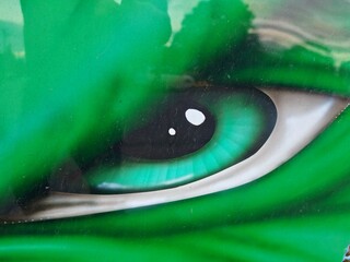 Close-up detail of green eye of giant green monster, showcasing fantasy creature's intense gaze and...