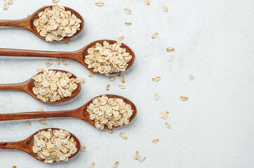 Oats arranged in wooden spoons on a light surface for a healthy breakfast option