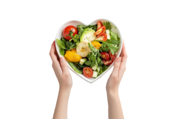 Hands holding a heart-shaped plate with fresh vegetables on a transparent background.
