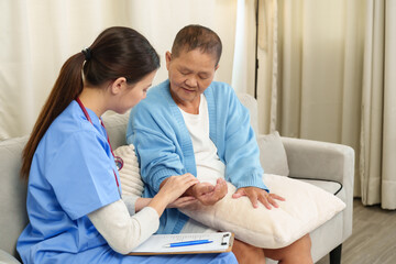 Physiotherapist assisting elderly patient, holding hand, seated on sofa, supportive care, rehabilitation session, recovery process, warm interaction, elderly care, thoughtful healthcare approach