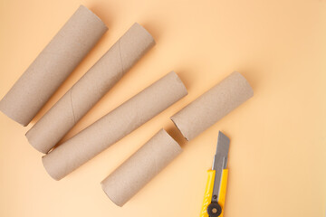 Cardboard tubes and utility knife on orange background, showing preparation for simple craft project, perfect for education publishers, DIY blogs, eco brands, kids workshops, home learning kits,