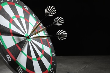 Targeting. Dart board with arrows on dark background, closeup. Space for text