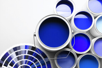 Cans with paint in shades of blue and color palette on white background, top view