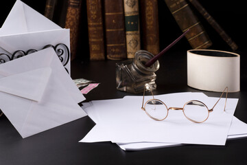 occhiali da lettura sopra a dei fogli di carta e dei vecchi libri,vecchie lettere con penna e calamaio.