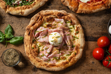 Overhead view of an Italian pizza topped with buffalo mozzarella and slices of mortadella, placed on a rustic wooden surface.