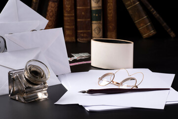 occhiali da lettura sopra a dei fogli di carta e dei vecchi libri,vecchie lettere con penna e calamaio.