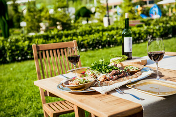 Delicious Grilled Steak meat with Sides BBQ Lunch with wine on nature in park by summer.